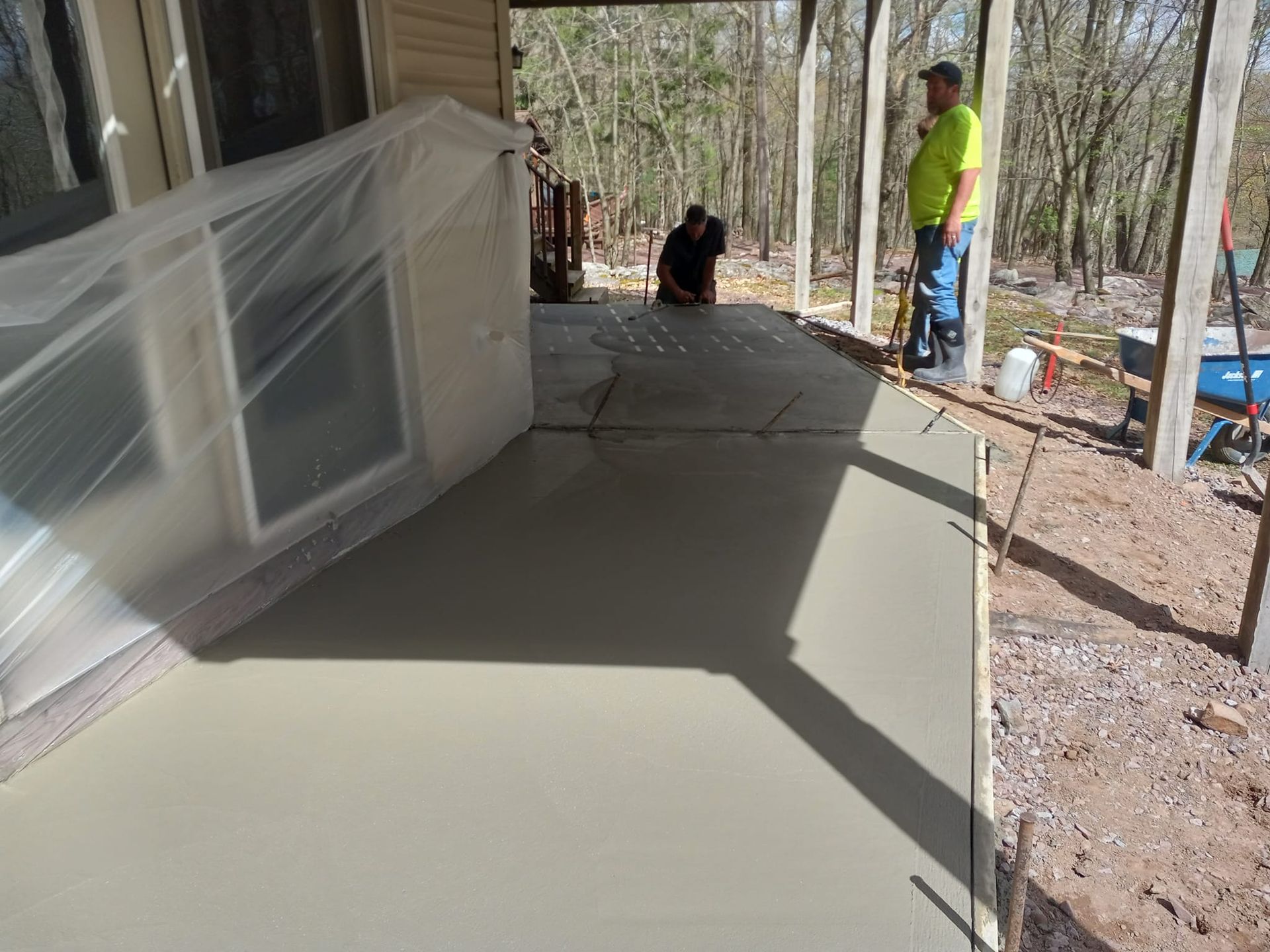 A man in a yellow shirt is standing on a concrete porch.