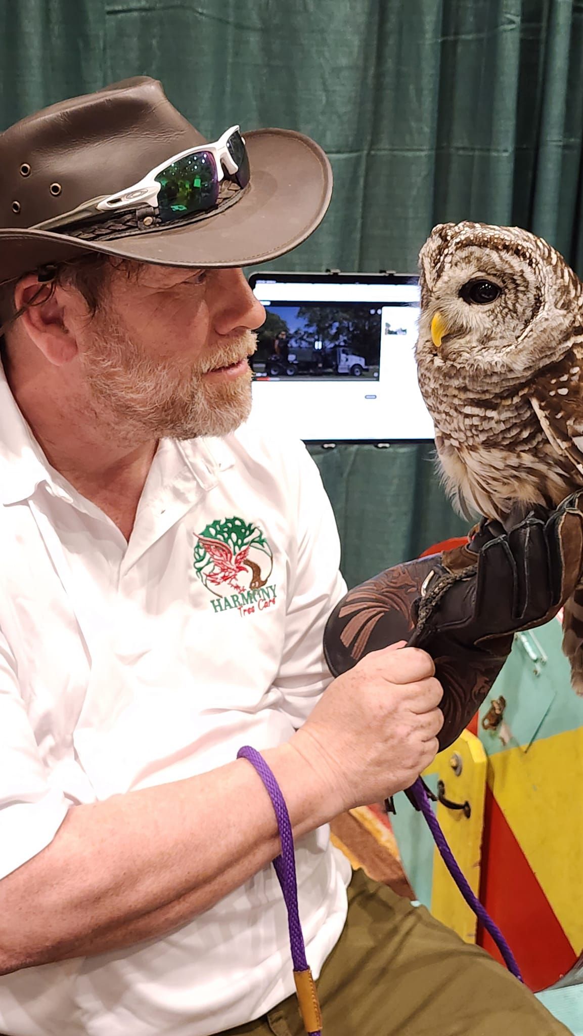 A man in a hat is holding an owl on his arm