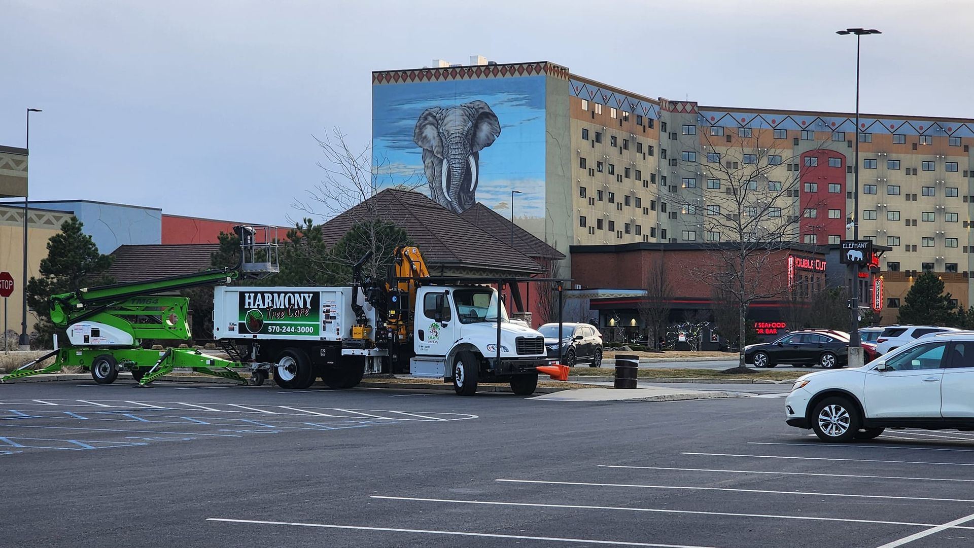 A white truck with a green box on the back is parked in a parking lot.