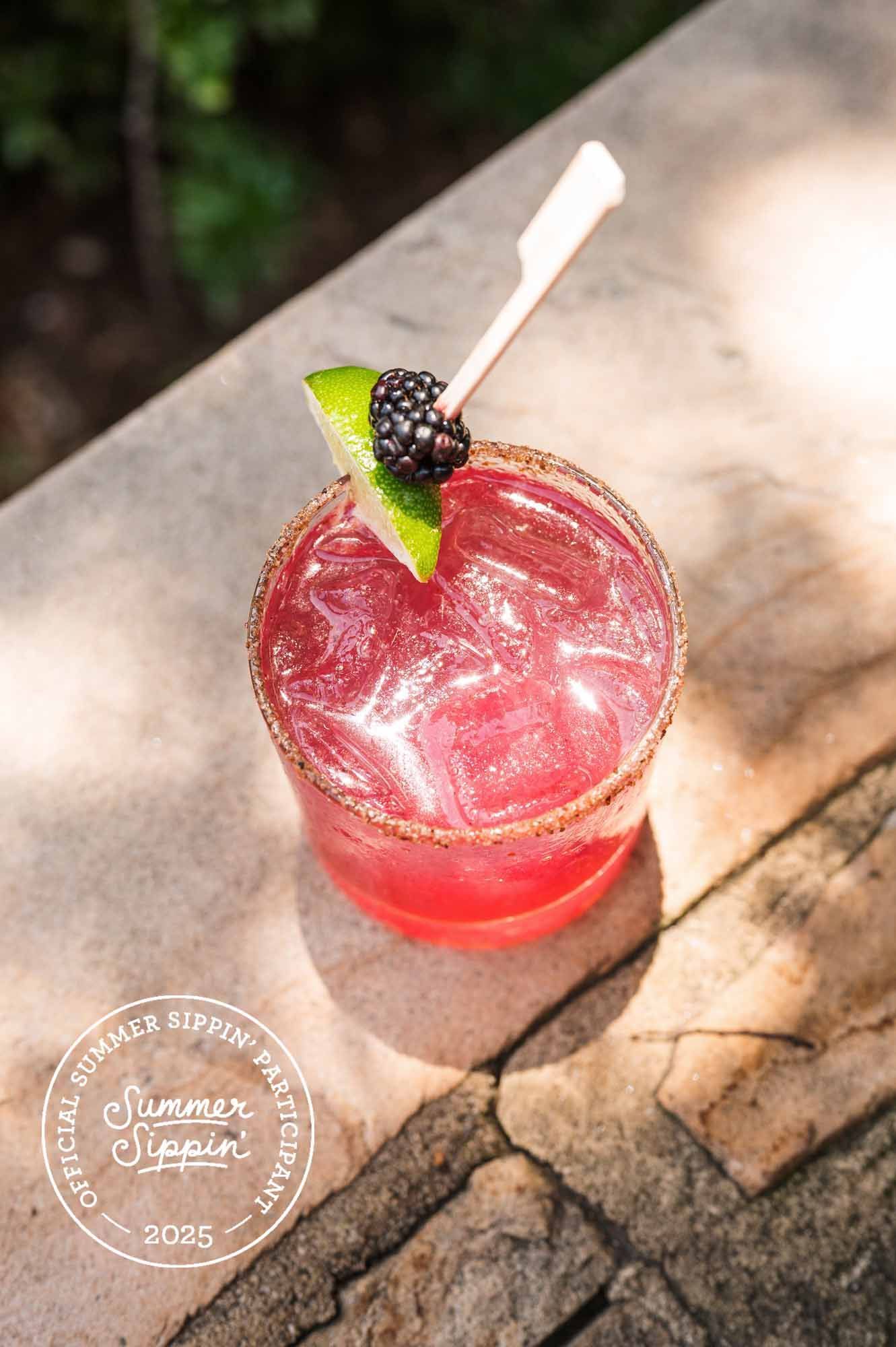 A glass of drink with lemon slices on a wooden table.
