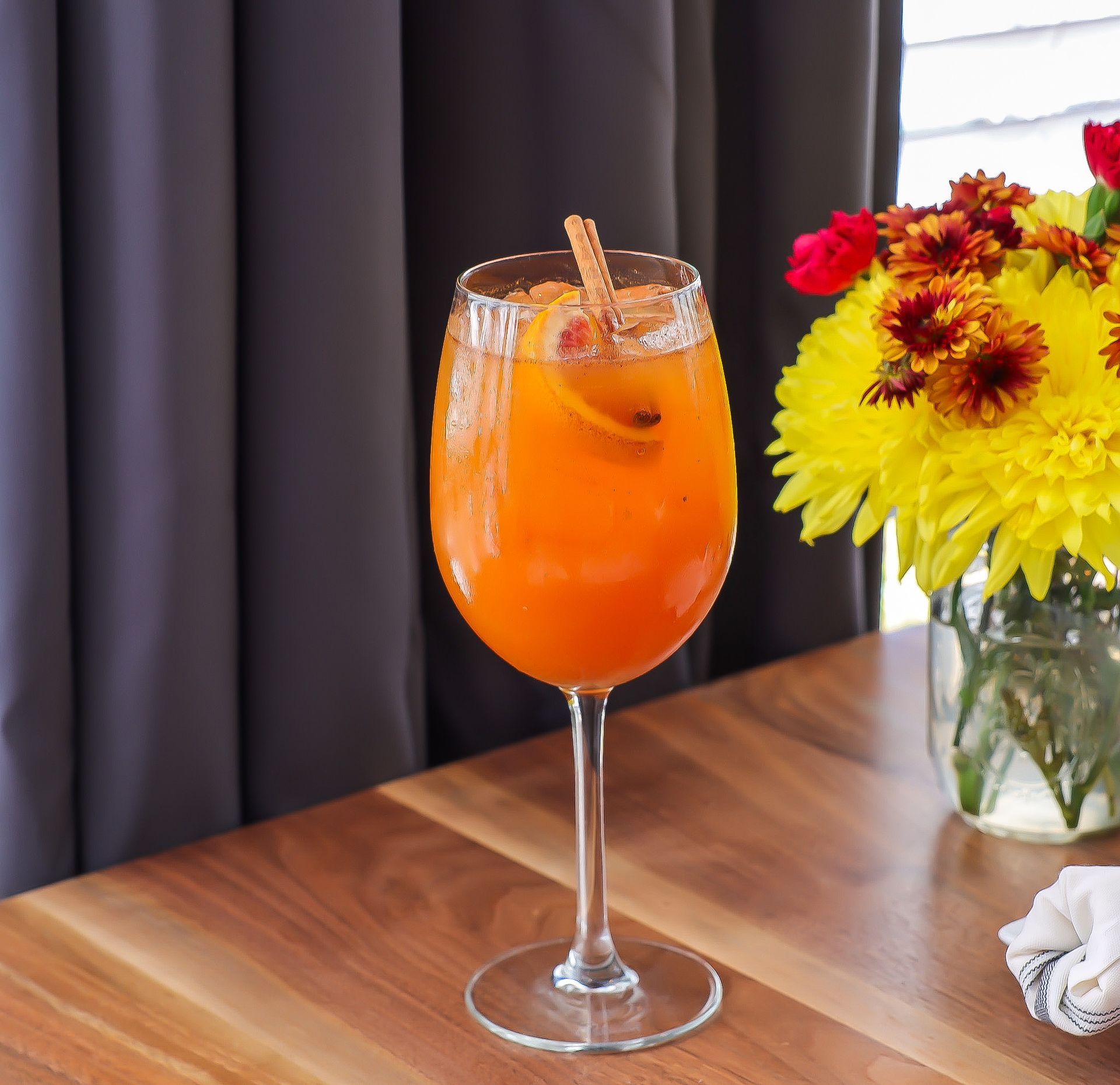 A close up of a plate of food with a glass of wine in the background