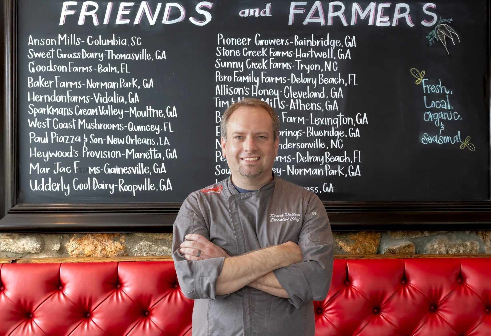 Chef standing in front of a chalkboard listing 
