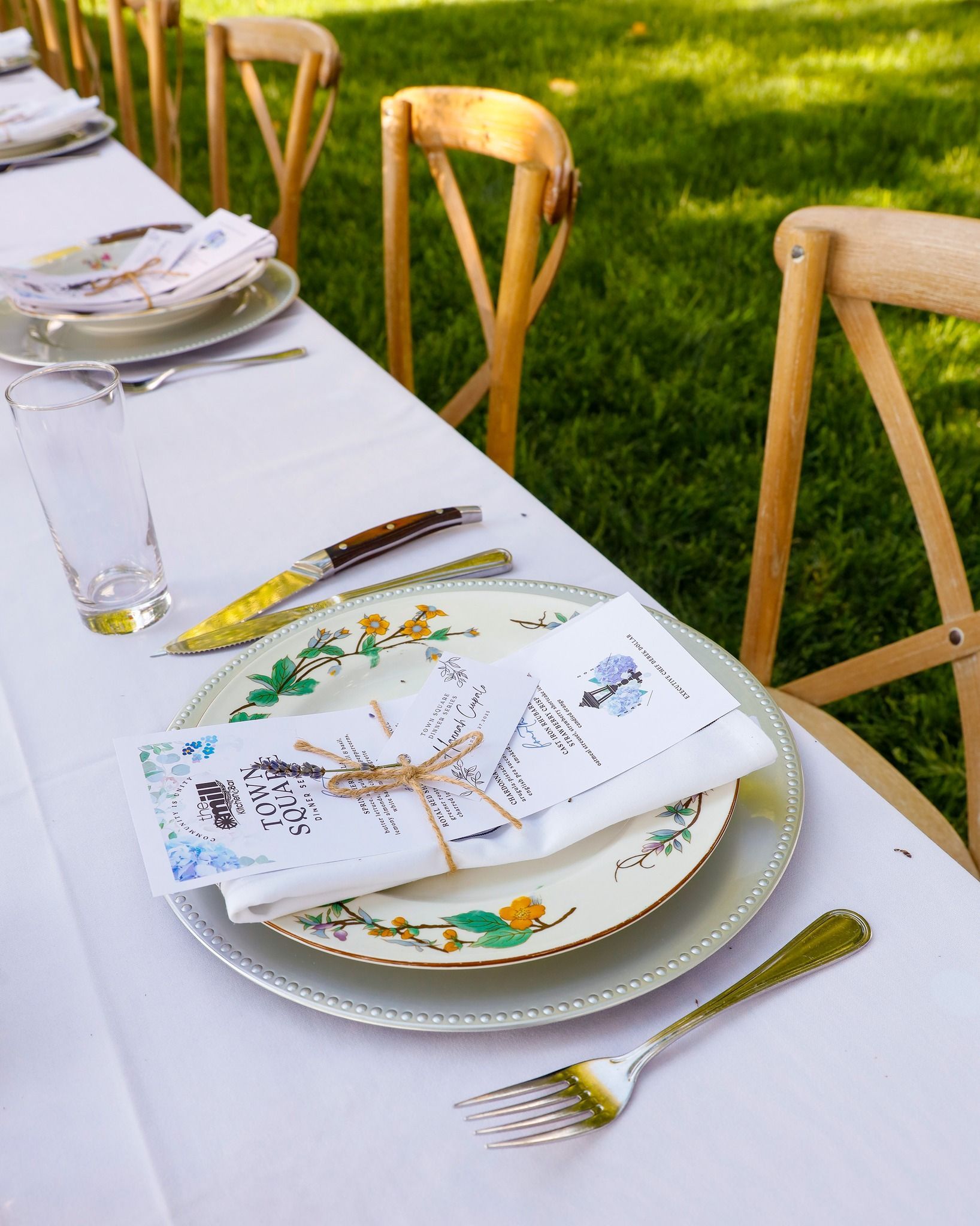 A table with plates , forks , knives and napkins on it.
