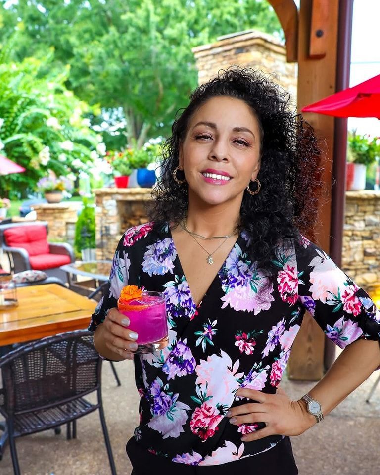 A man in a black shirt is holding two bottles of wine.
