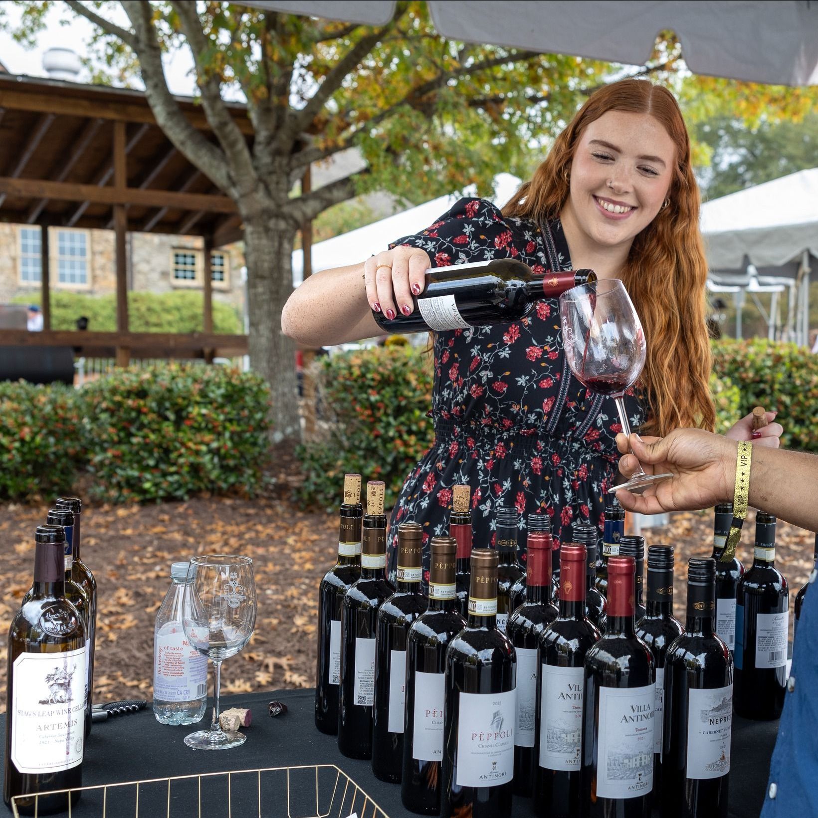 A woman is pouring a glass of wine from a bottle