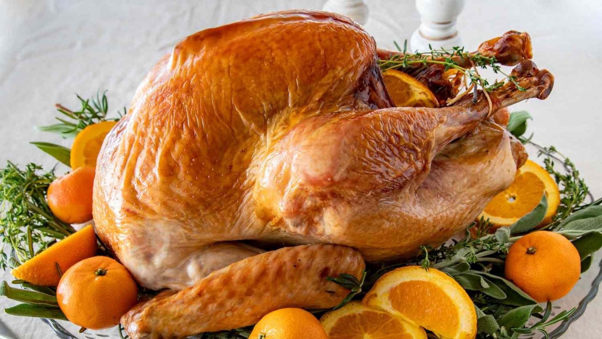 Roasted turkey on a platter, garnished with oranges and herbs.