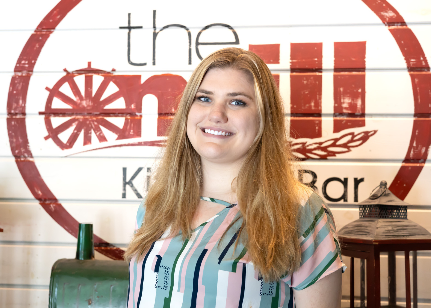 A woman is standing in front of a sign that says the mill