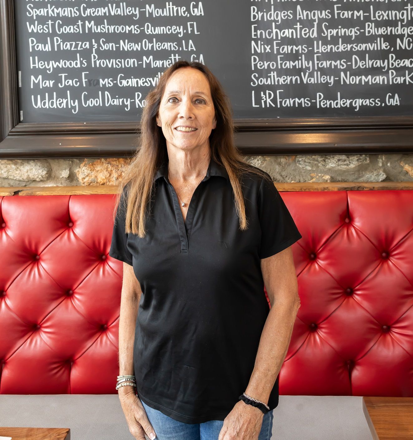 A woman in a black shirt is standing in front of a red couch