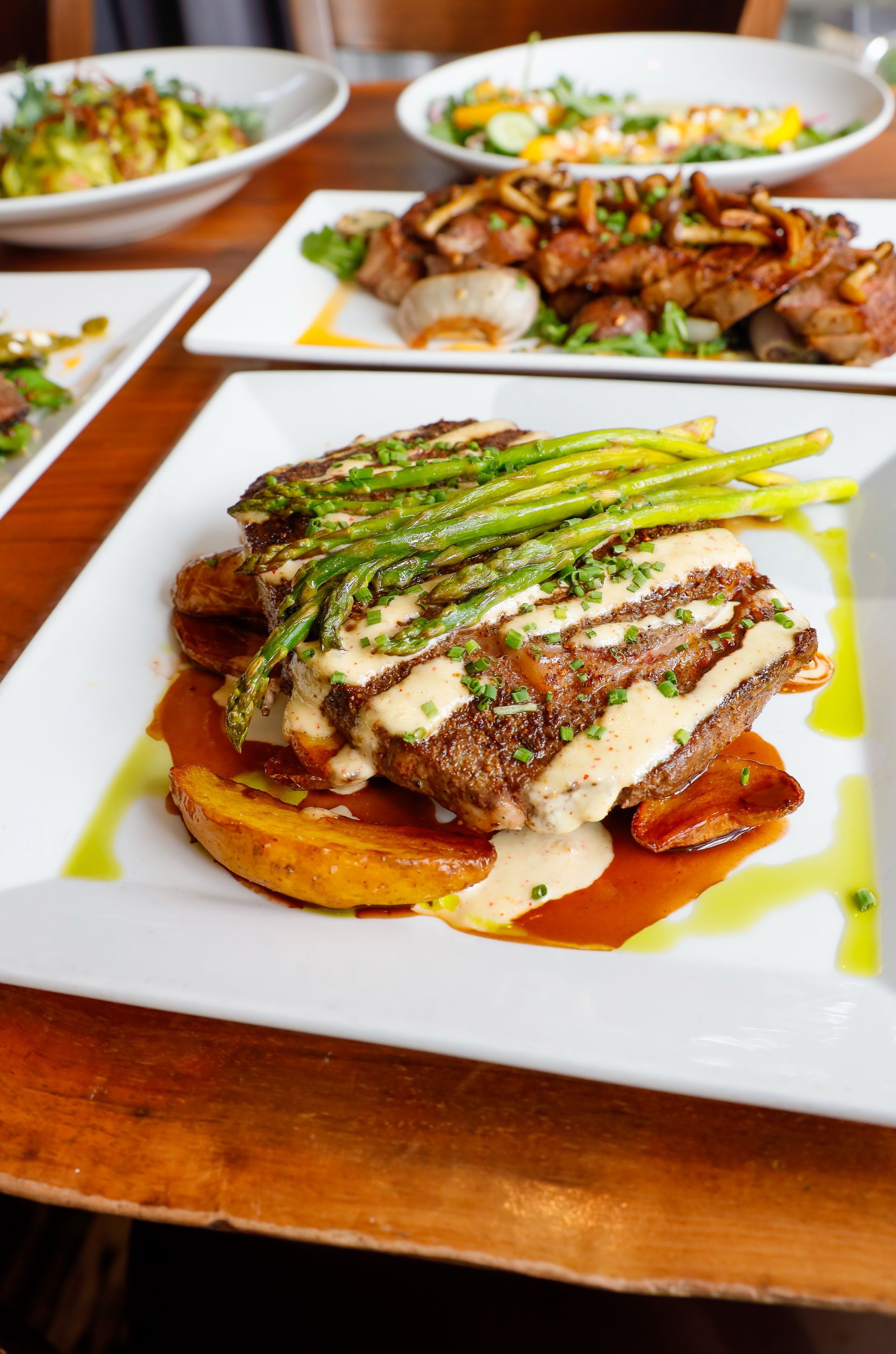 A white plate topped with a steak and asparagus on a wooden table.
