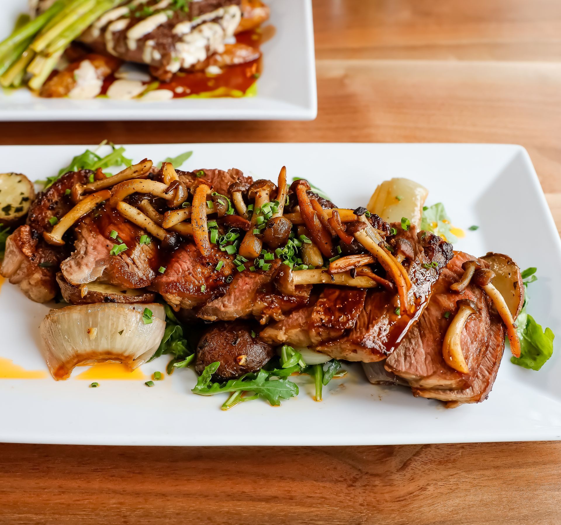 A white plate topped with meat and vegetables on a wooden table