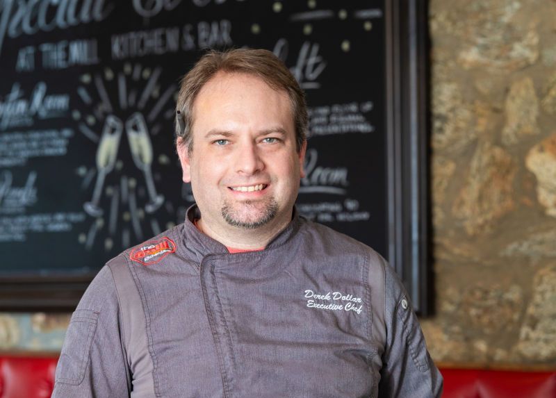 A man in a chef 's uniform is holding a plate of food