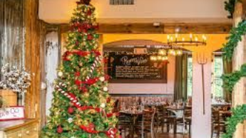 A christmas tree is sitting in the middle of a room in a restaurant.
