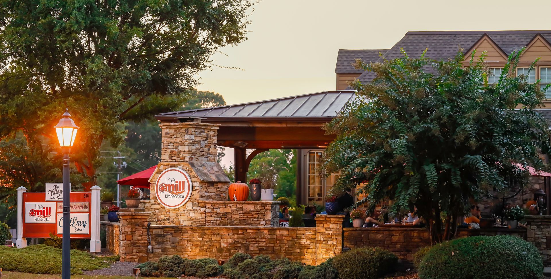 Restaurant exterior with stone facade, sign, and outdoor seating.