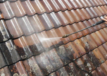 A Person Is Cleaning A Roof With A High Pressure Washer — Rooftech Roofing Services in Ballina, NSW