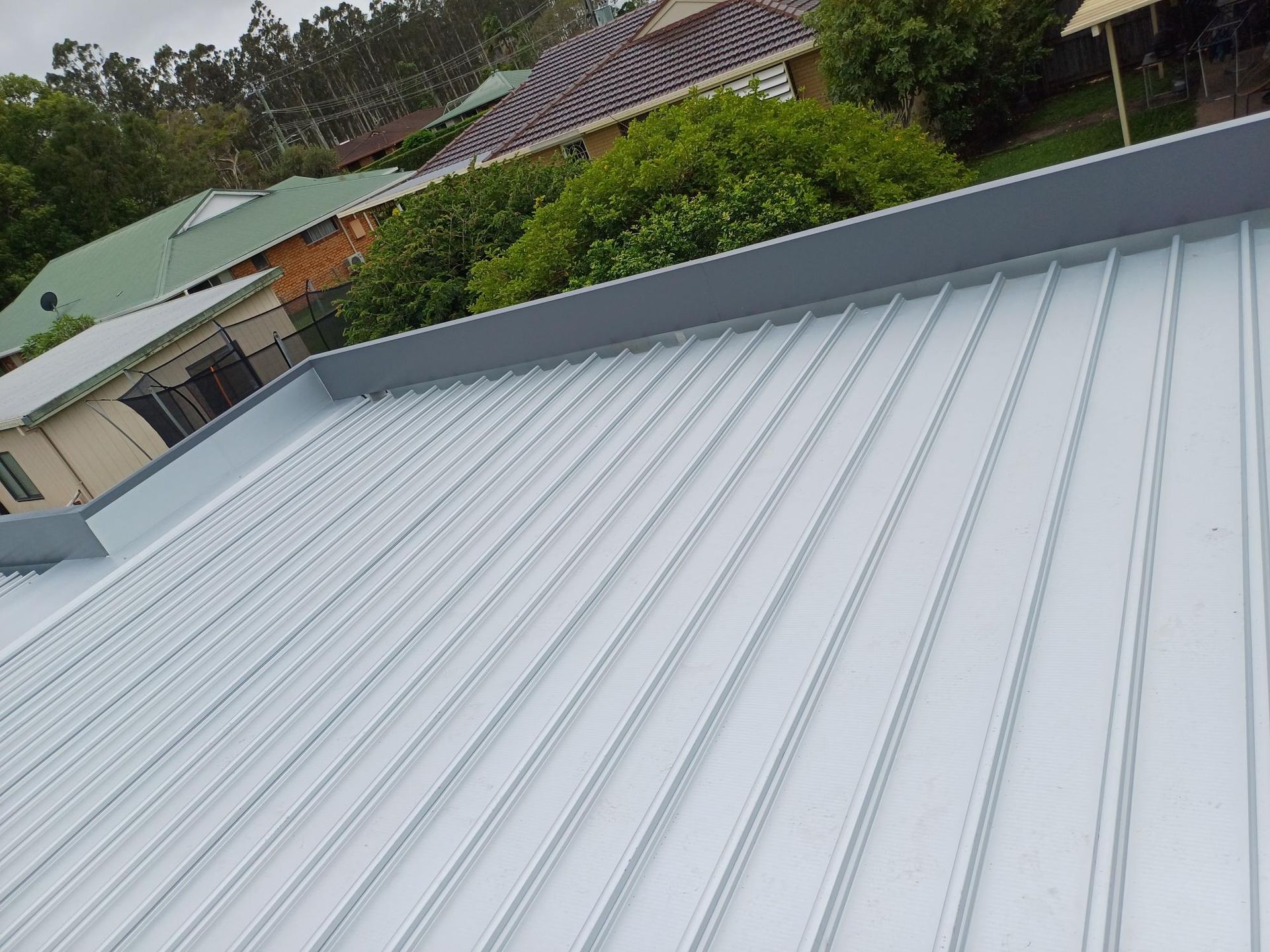 The Roof Of A House With A Metal Roof And Trees In The Background — Rooftech Roofing Services in Yamba, NSW