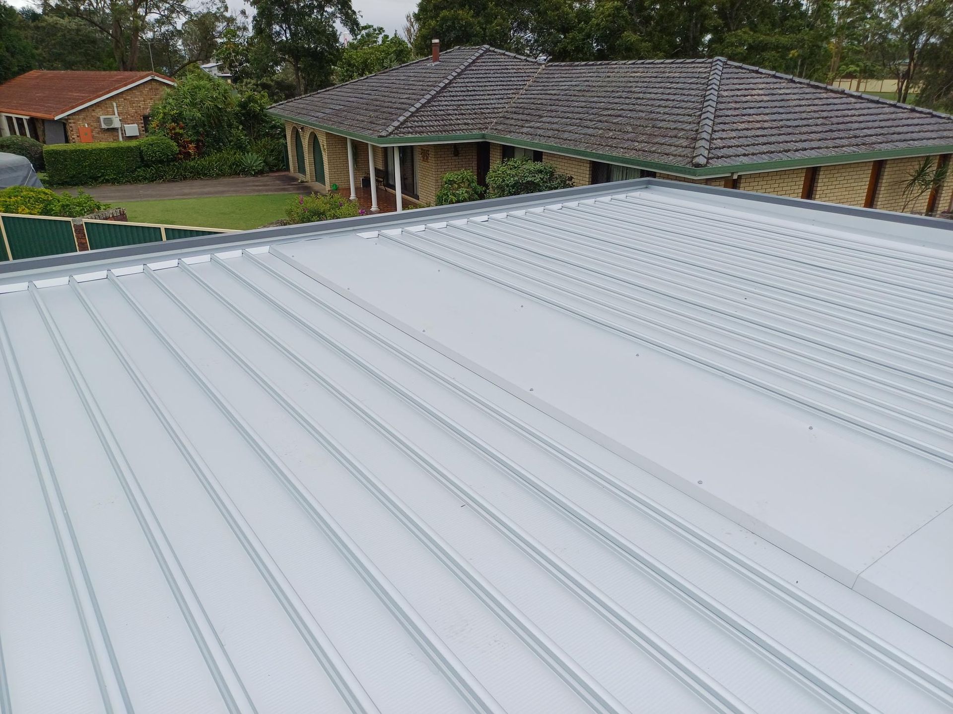A Couple of Men Are Working on A Red Roof — Rooftech Roofing Services in Ballina, NSW