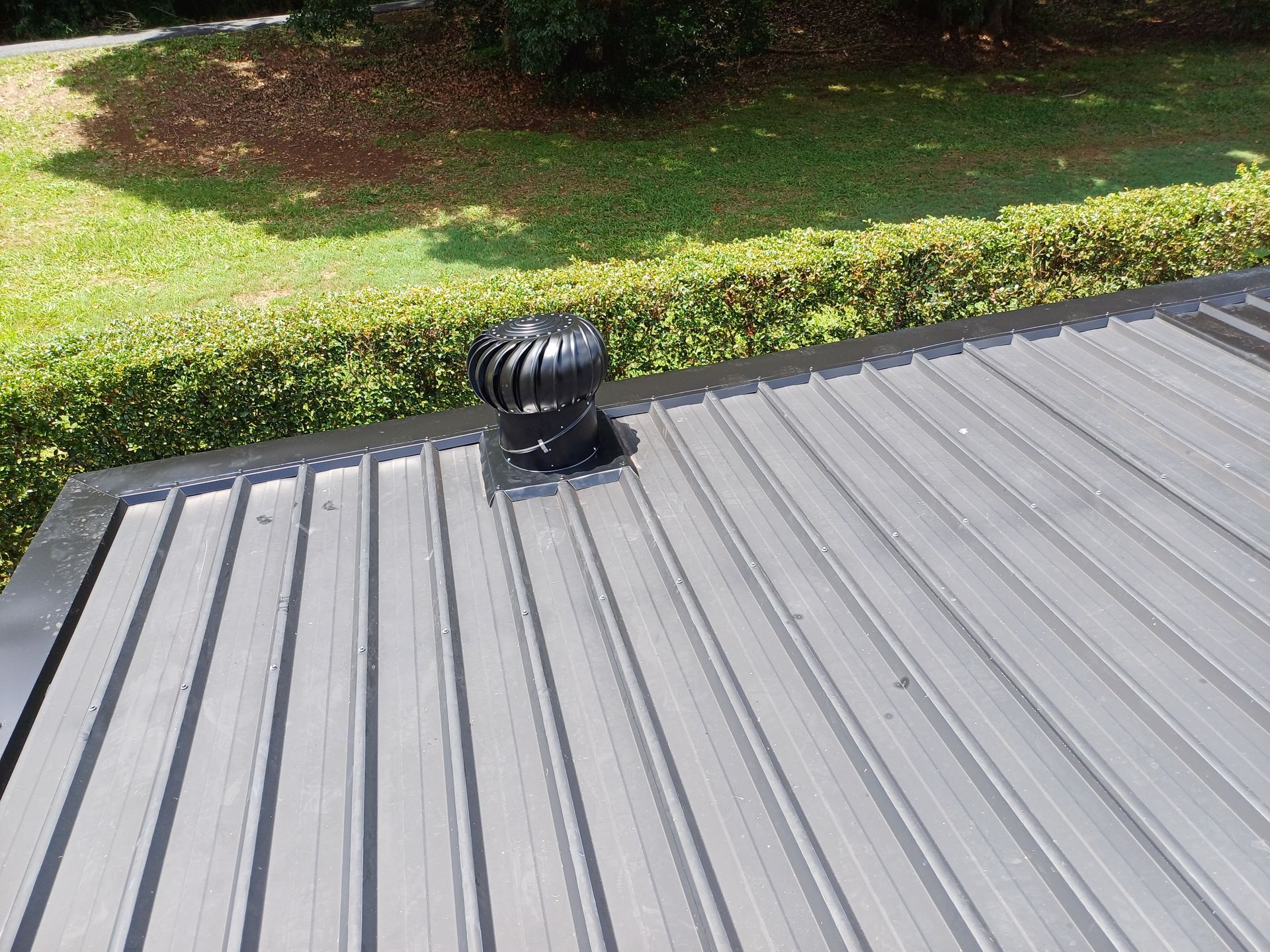 A Grey Roof With A Black Whirleybird On It— Rooftech Roofing Services in Ballina, NSW
