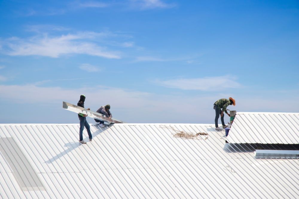 Three Men Are Working on A White Roof — Rooftech Roofing Services in Yamba, NSW