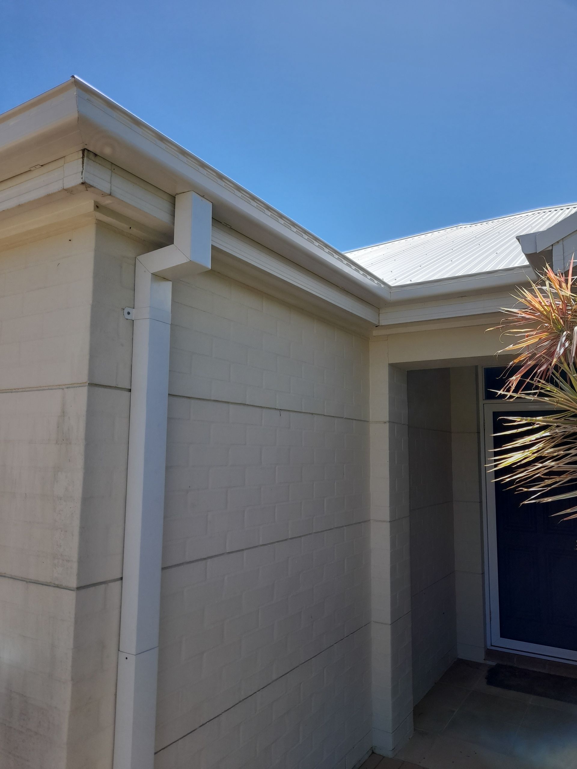 A White House With A White Gutter On The Side Of It — Rooftech Roofing Services in Byron Bay, NSW