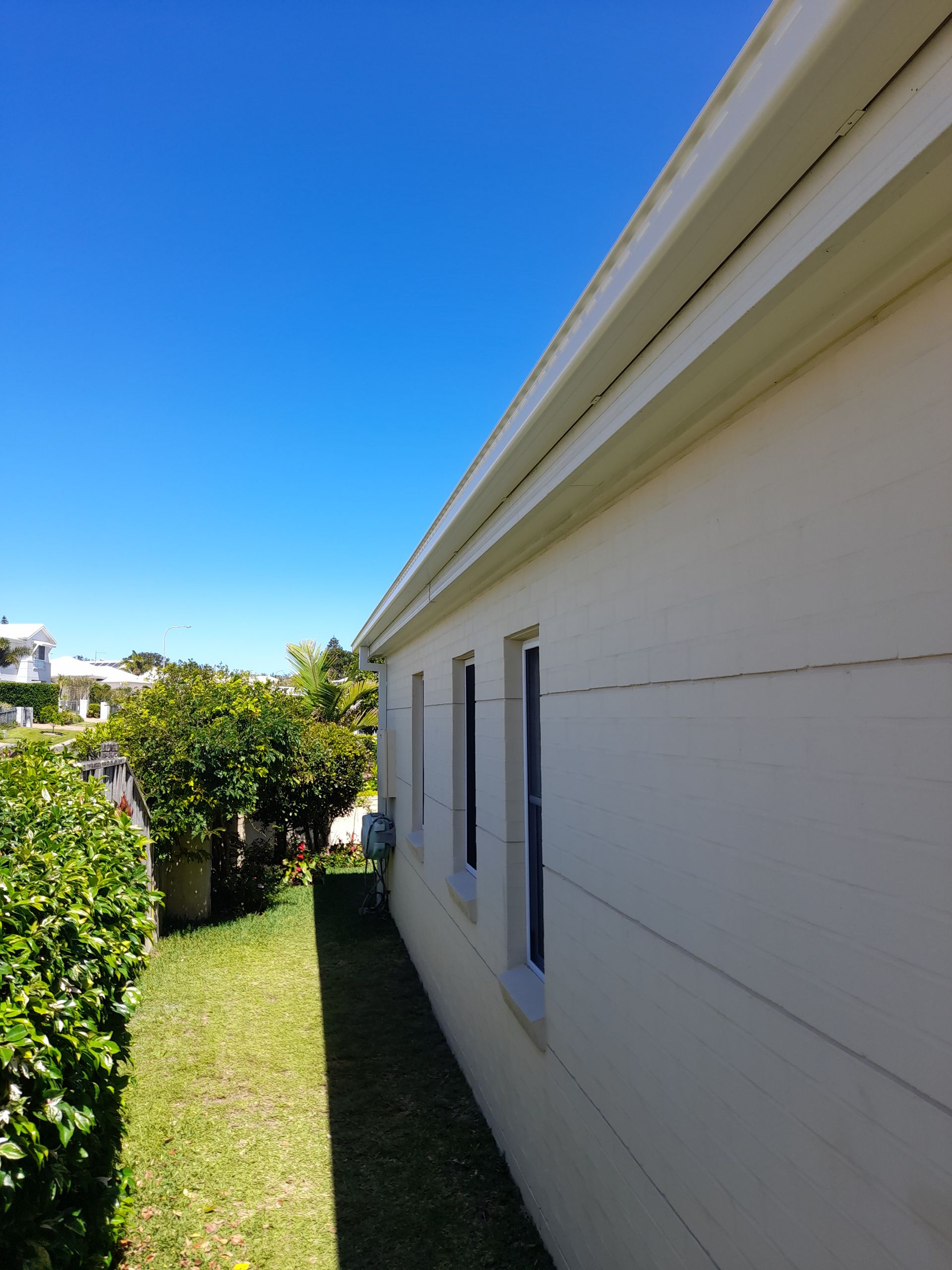 A White Brick House With A White Gutter — Rooftech Roofing Services in Byron Bay, NSW