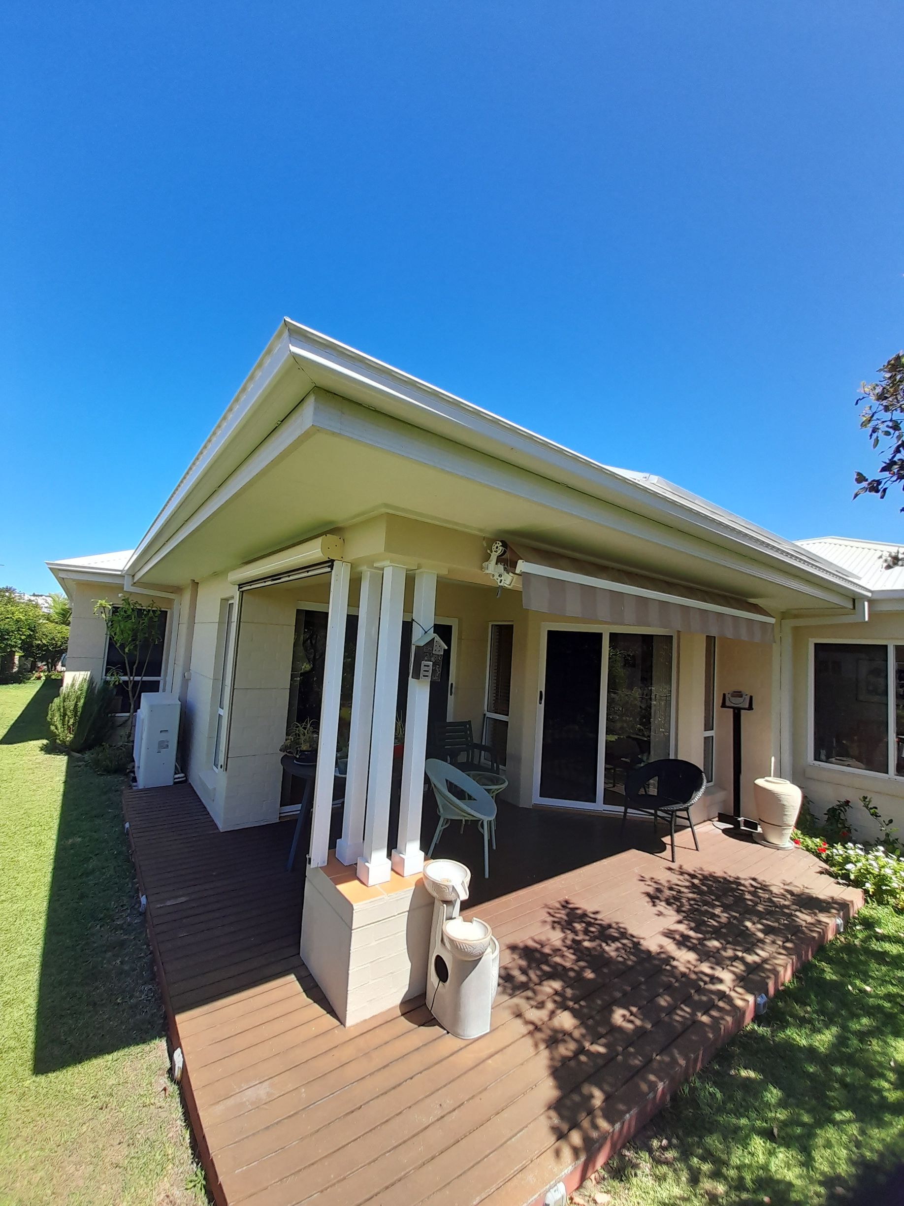 A White House With A White Roof And Wooden Deck — Rooftech Roofing Services in Ocean Shores, NSW
