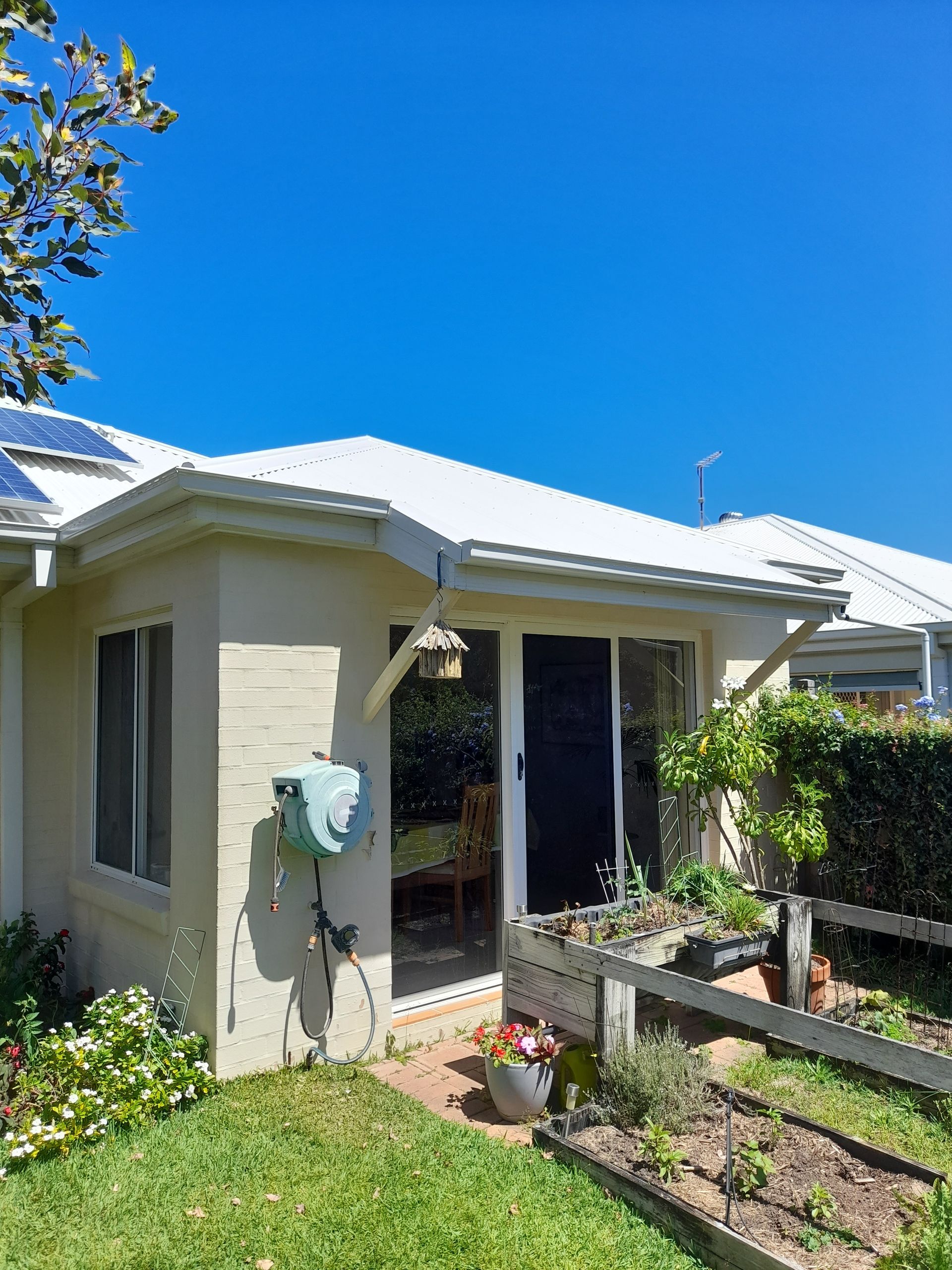 A White Brick House With A White Roof— Rooftech Roofing Services in Bangalow, NSW