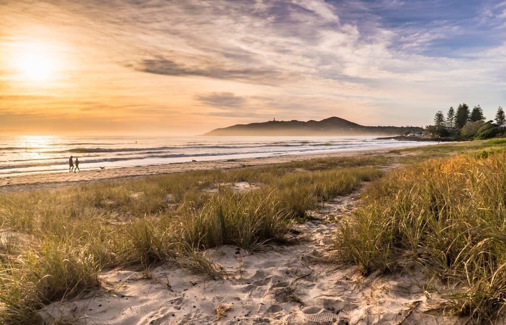 A Couple Is Walking on A Beach at Sunset — Rooftech Roofing Services in Byron Bay, NSW