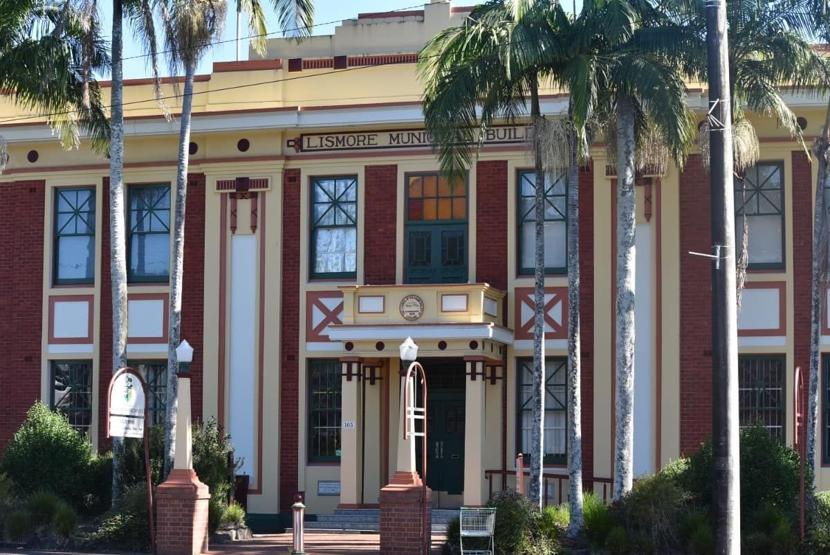 A Large Brick Building with Palm Trees in Front of It — Rooftech Roofing Services in Lismore, NSW