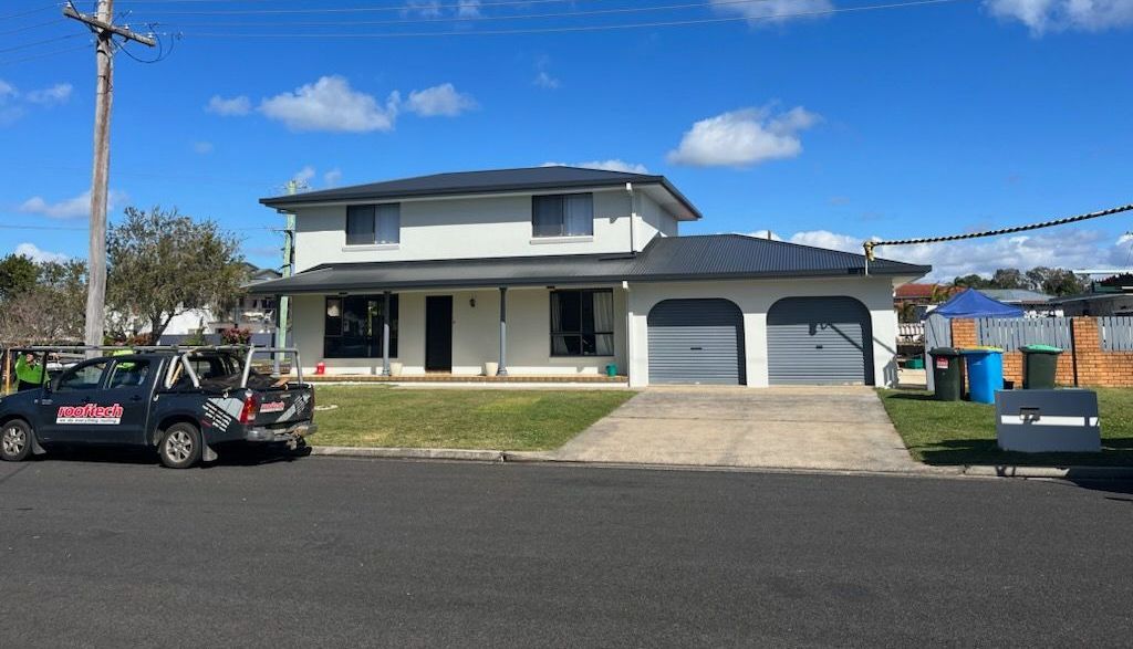 A White House With A Black Truck Parked In Front Of It — Rooftech Roofing Services in Goonellabah, NSW