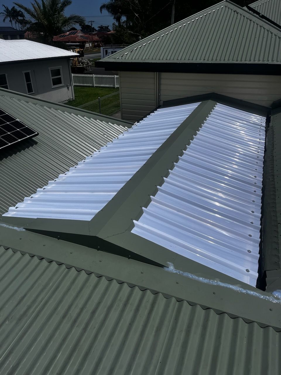 The Roof Of A House Has A White Roof And Solar Panels On It — Rooftech Roofing Services in Yamba, NSW