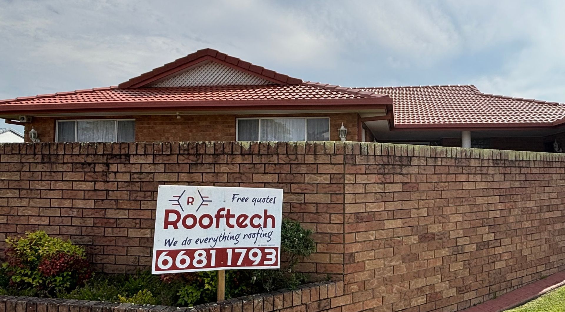 A House With A Red Roof And A Sign Out The Front — Rooftech Roofing Services in Ballina, NSW