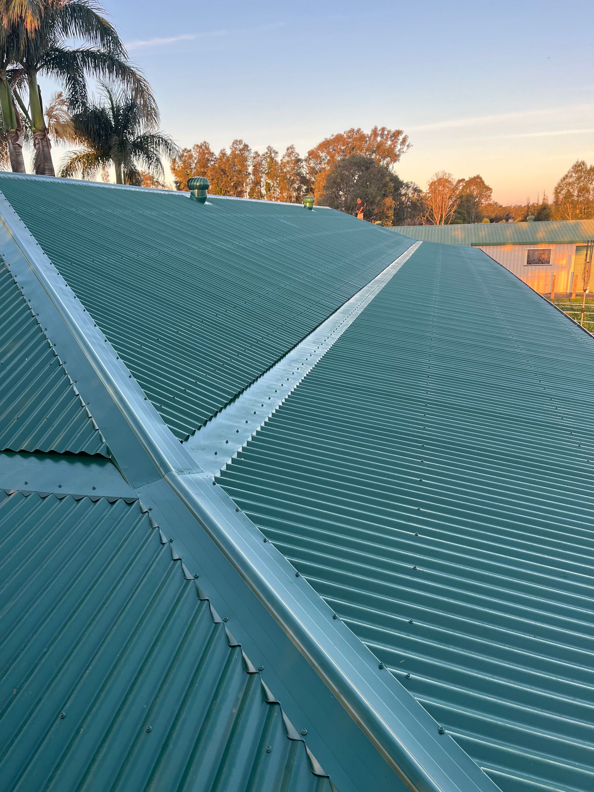 A Green Corrugated Metal Roof With A Gutter On The Side Of It — Rooftech Roofing Services in Byron Bay, NSW