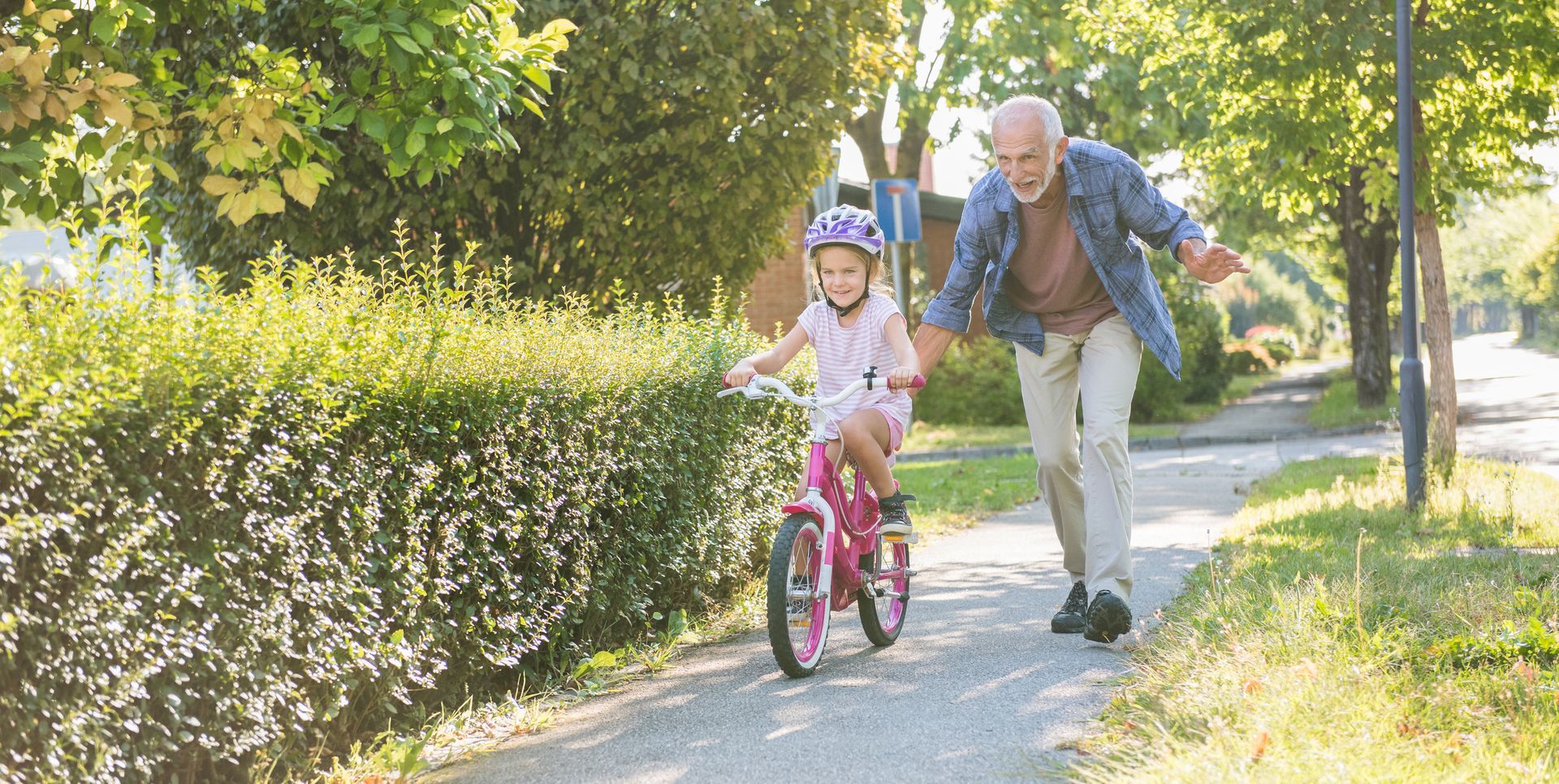 An elderly man and a small girl riding a bike, sharing a moment of joy in a bright, outdoor environm