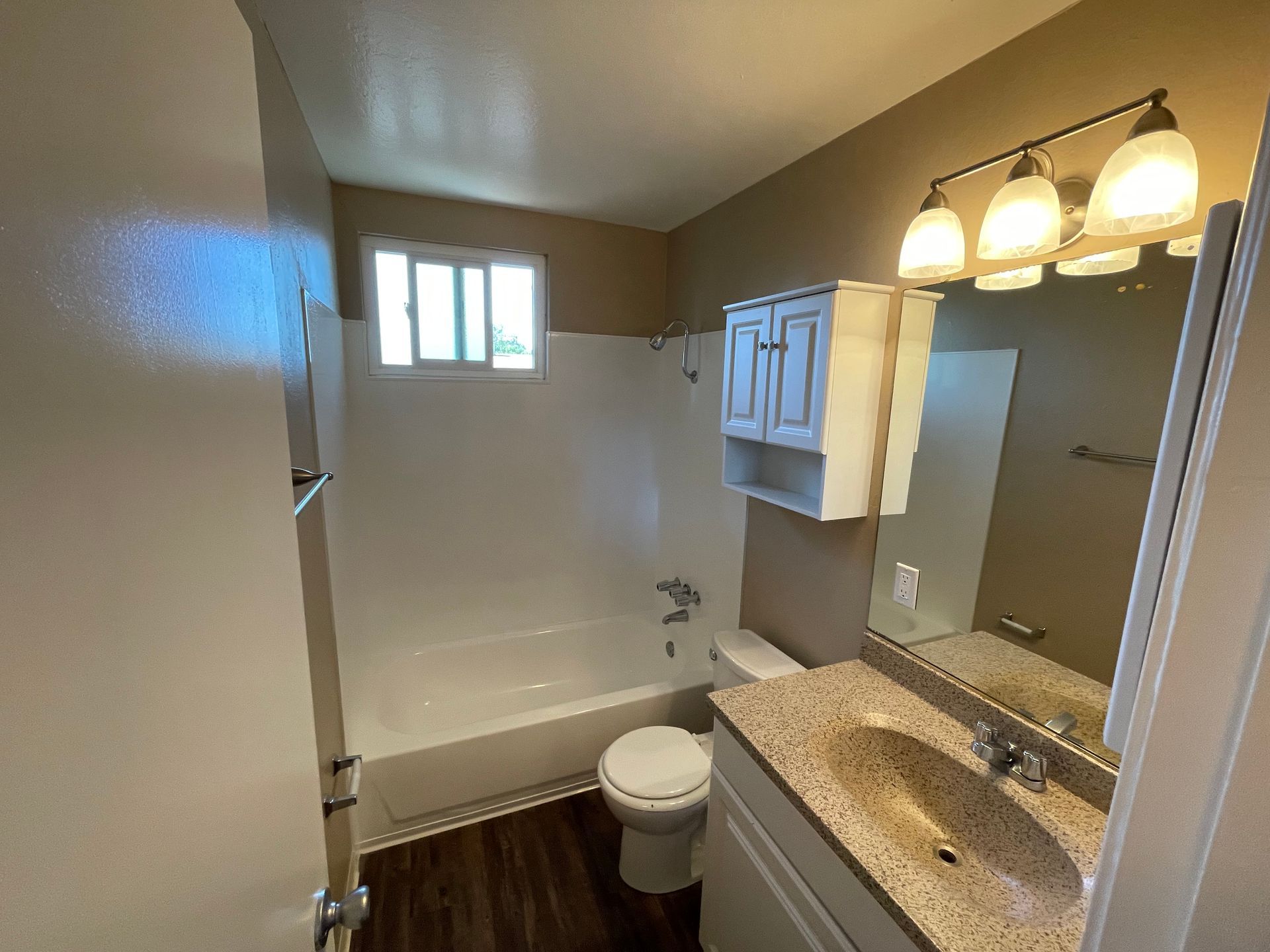A bathroom with a toilet , sink , bathtub and mirror.