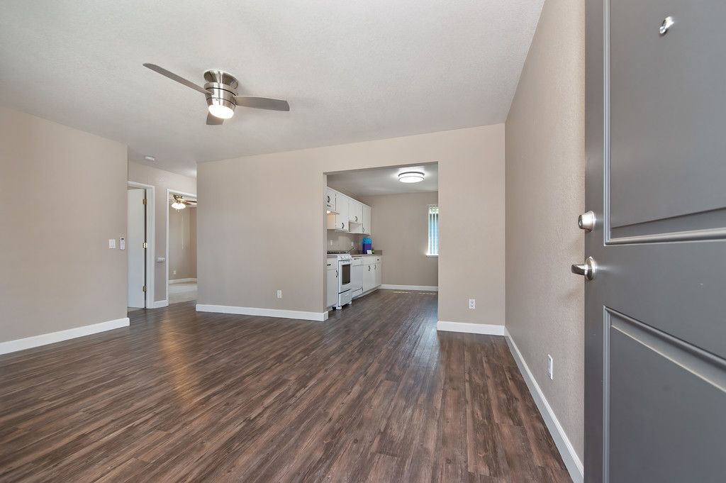 An empty living room with hardwood floors and a ceiling fan.