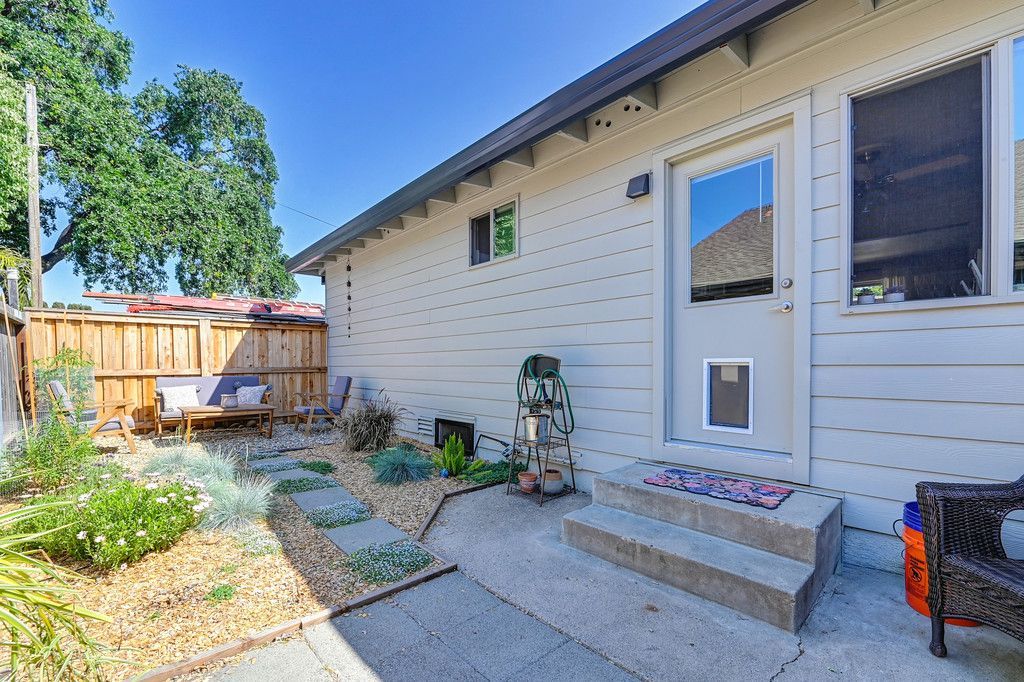 A white house with a dog door and a patio in front of it.