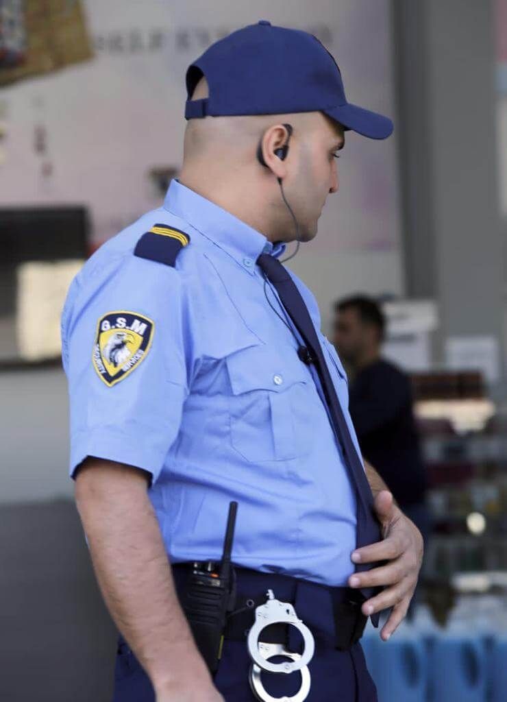 Person in hazmat suit disinfecting a room with fog-like spray; room with clothes rack, sofa, and vase.