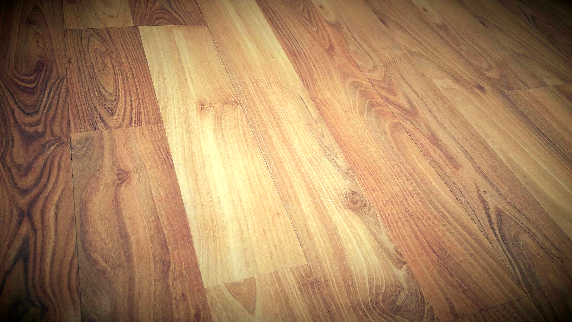 Wooden laminate flooring, light brown and tan planks, diagonally oriented.