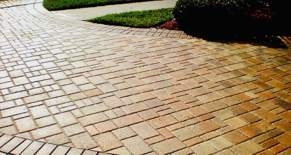 Brick driveway with curved border, next to a green lawn.