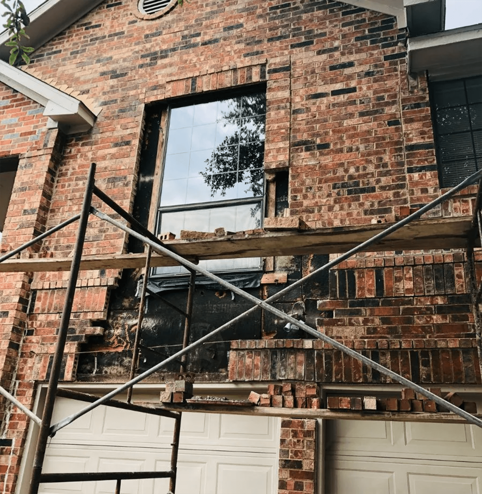 Brick house with a window being repaired; scaffolding and scattered bricks visible.