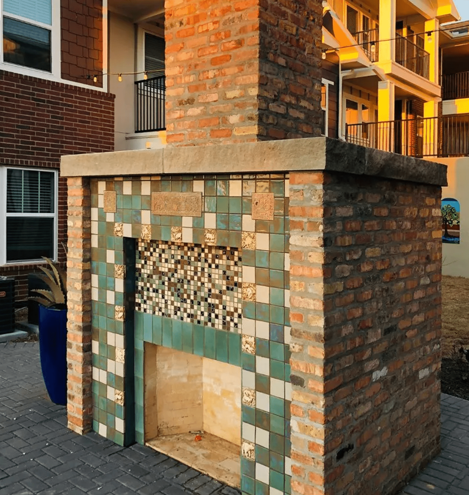 Brick outdoor fireplace with turquoise and tan tiled front.