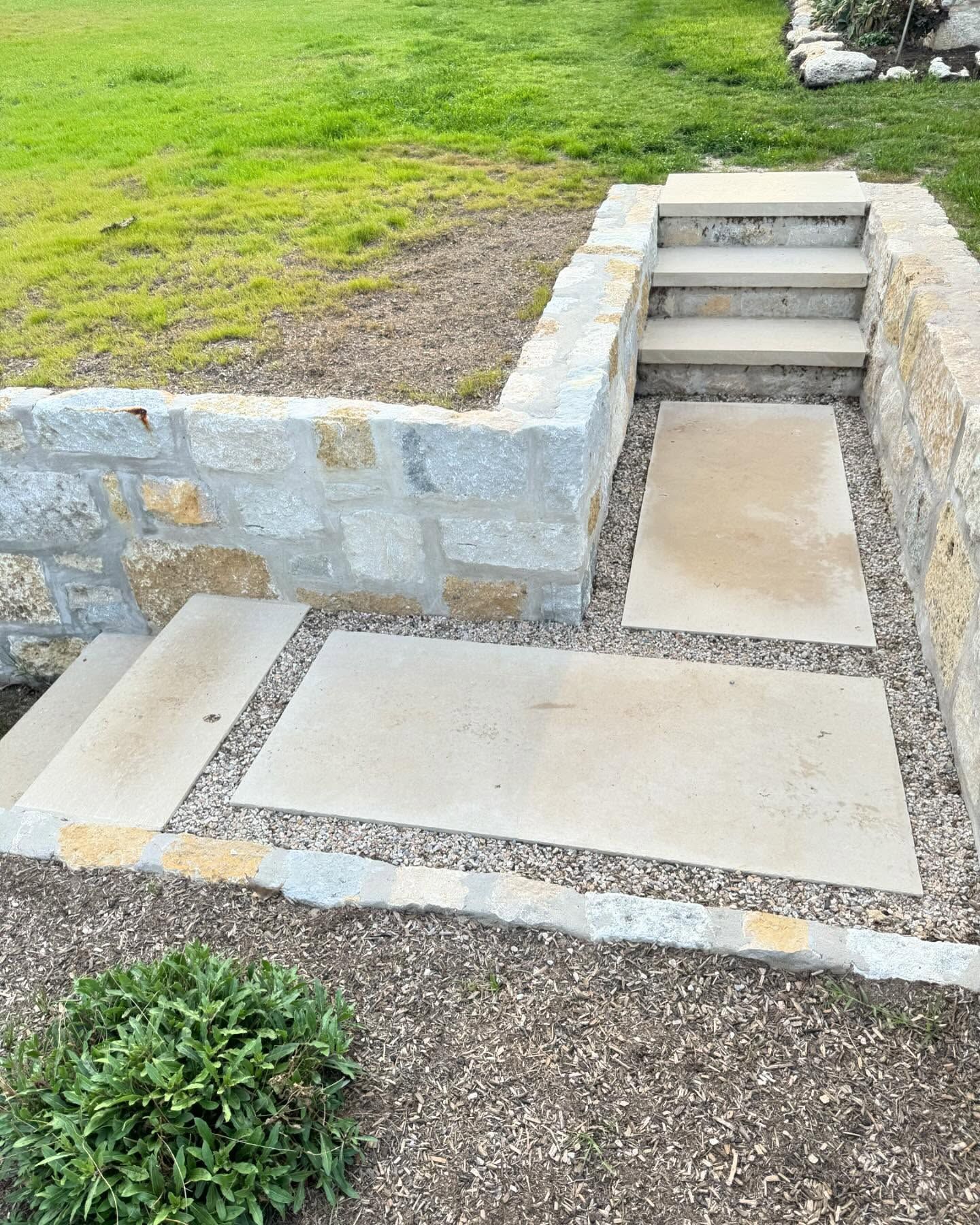 Stone steps and pathway in a garden with a retaining wall. Gravel surrounds the pathway.
