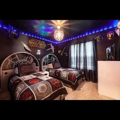 Star Wars-themed bedroom with two beds, dark decor, and galaxy lights.