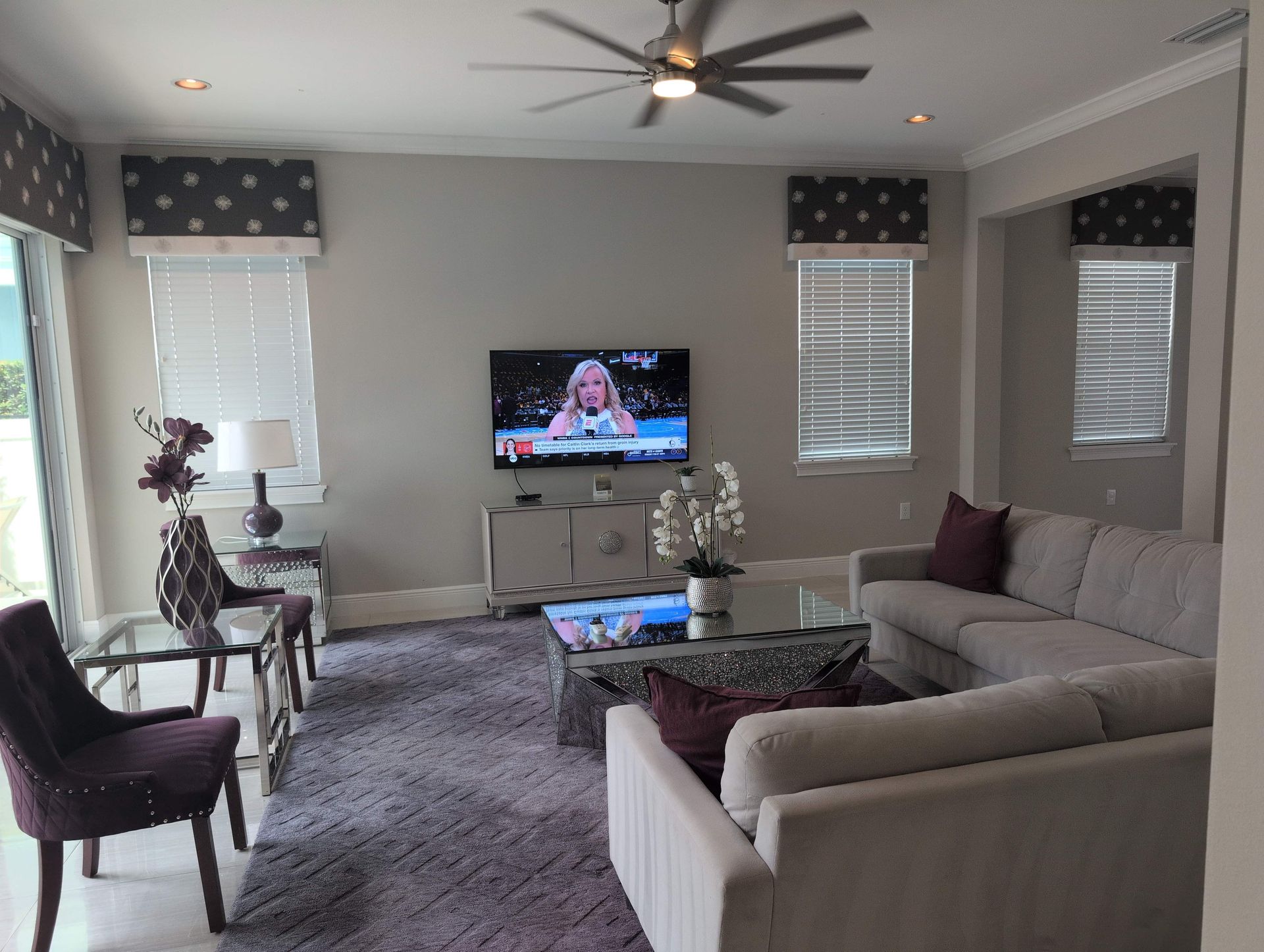 Living room with gray walls, a sectional sofa, and a TV mounted on the wall.