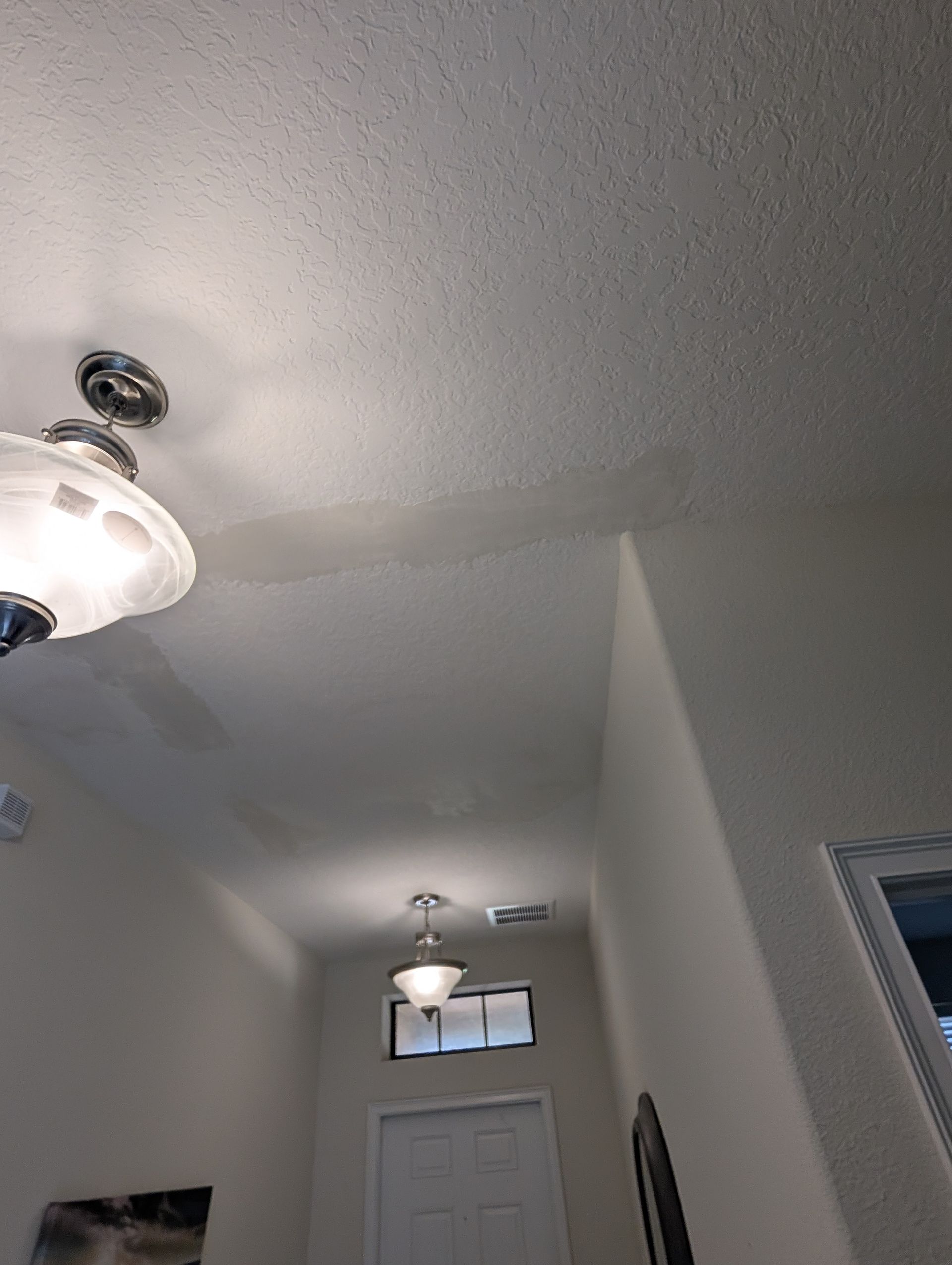 A view up at a hallway ceiling with lights and a patch of discoloration.
