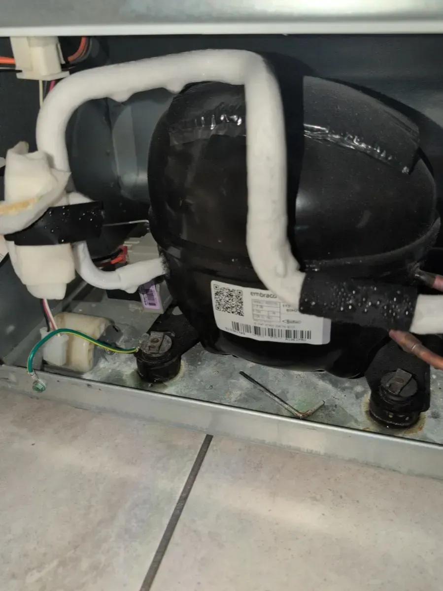 Refrigerator compressor with white insulation and a QR code, on a metal base.