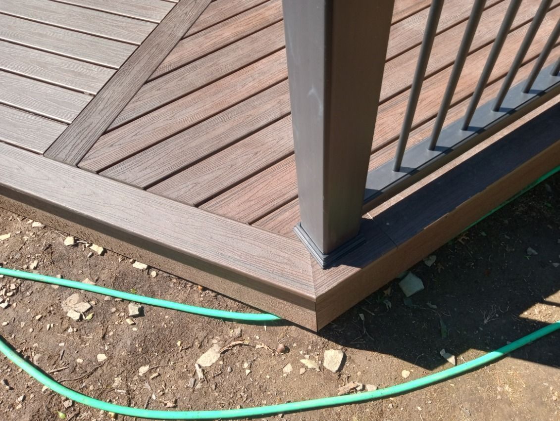 Close-up of a deck corner, with brown composite decking, railing, and post.