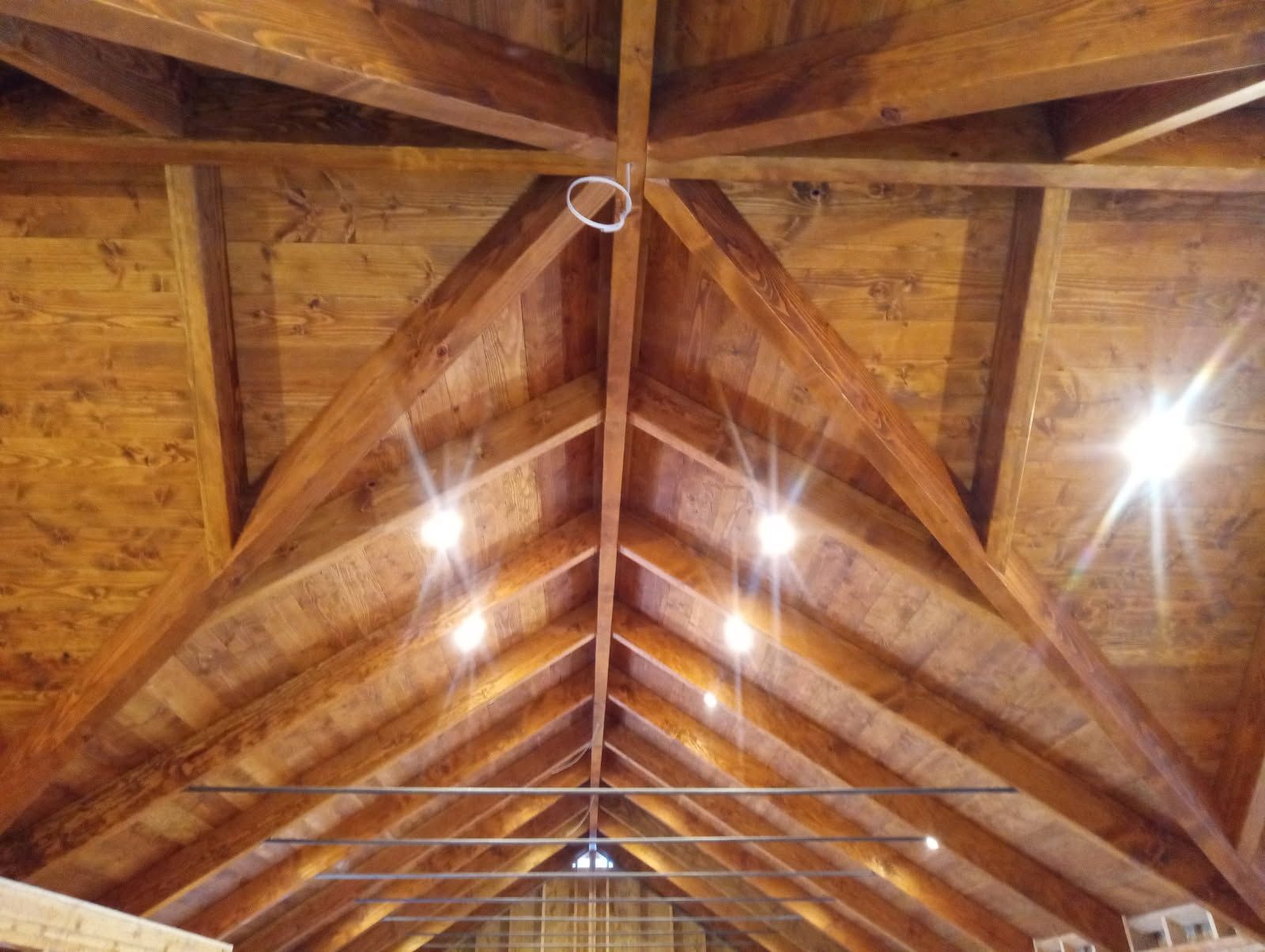 Wooden ceiling with exposed beams, recessed lights, and a hanging light fixture.
