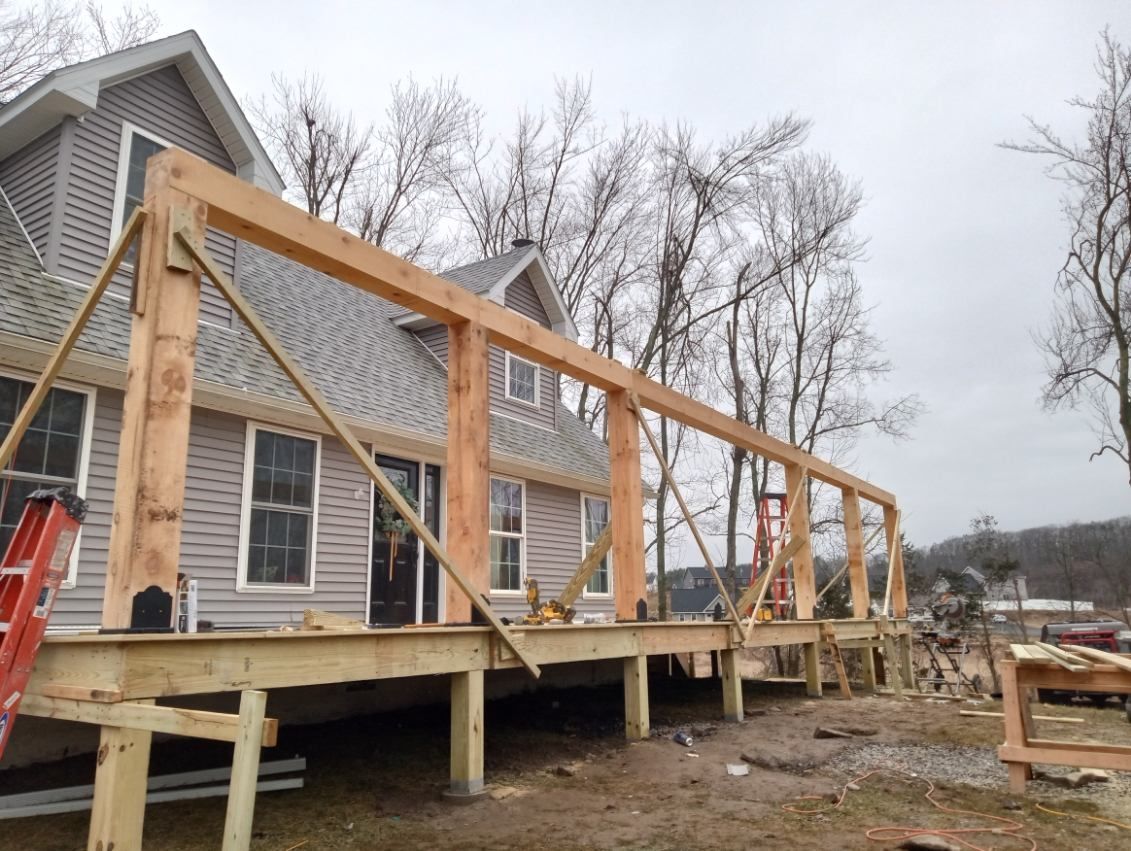 Wooden deck construction in progress next to a house with gray siding.