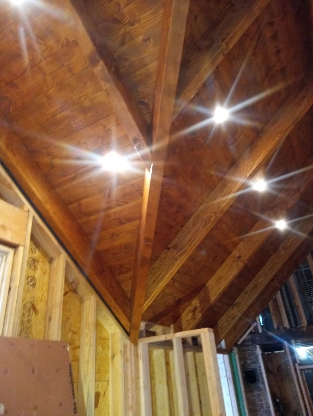 Wooden ceiling with recessed lights, under construction.